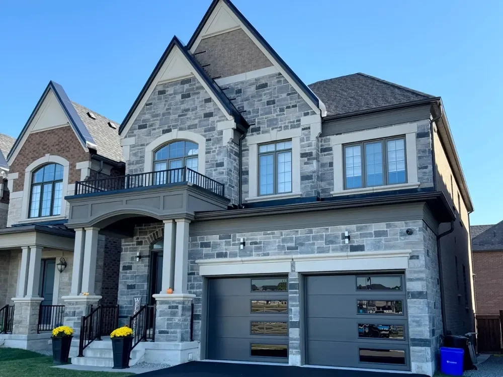 Dark brown modern flush garage doors with windows on a home in Barrie