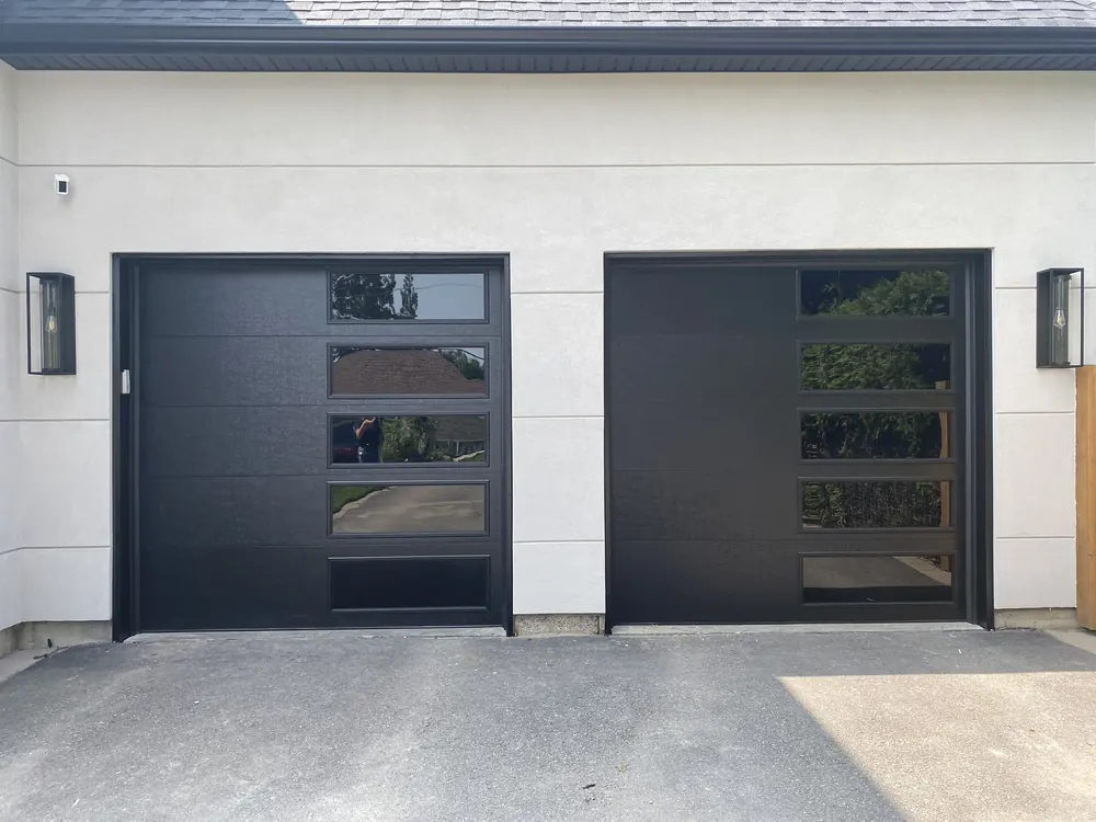 Black modern flush garage doors with windows on a home in King City