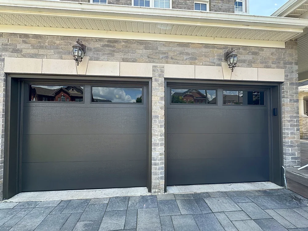 Black modern flush garage doors with windows on a home in King City