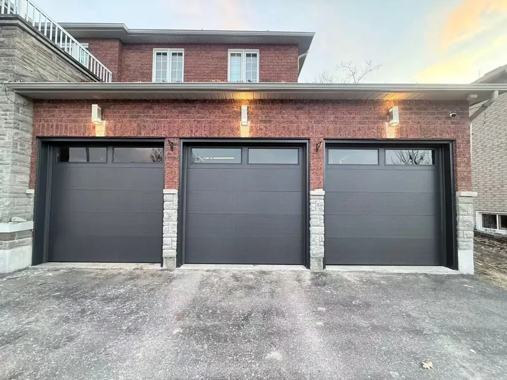 Black modern flush garage doors with windows on a home in Newmarket