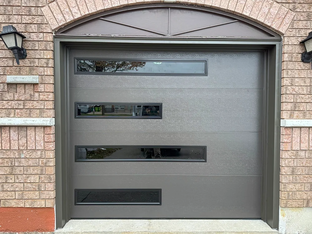 Dark brown modern flush garage door with slim glass strips on a home in North York