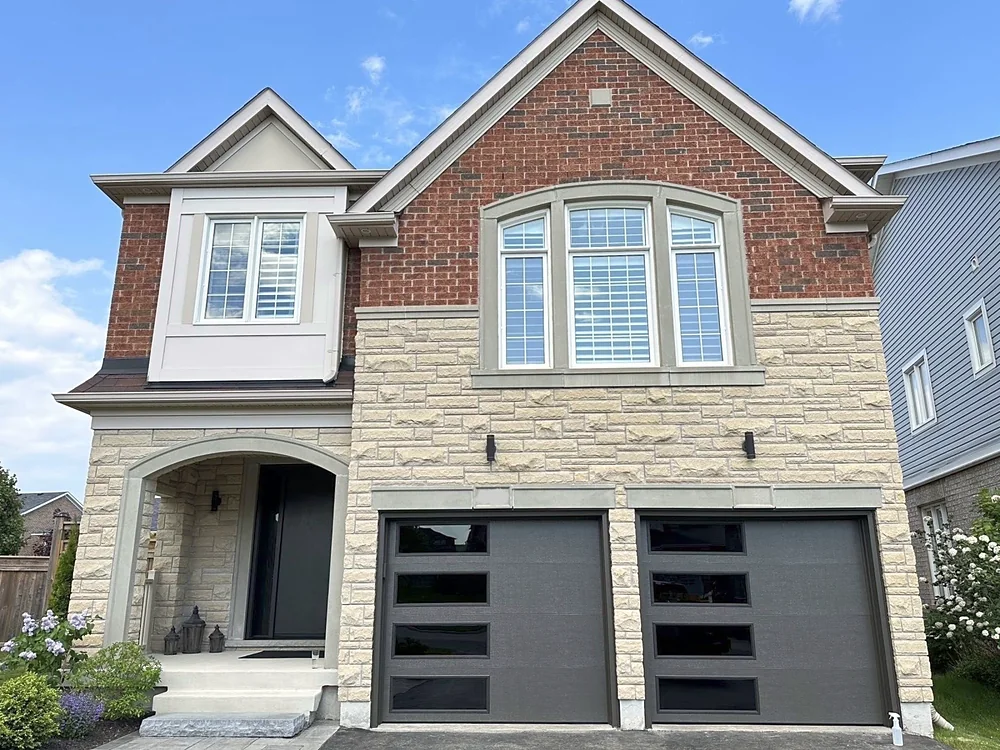 Dark brown modern flush garage doors with windows on a home in Oshawa
