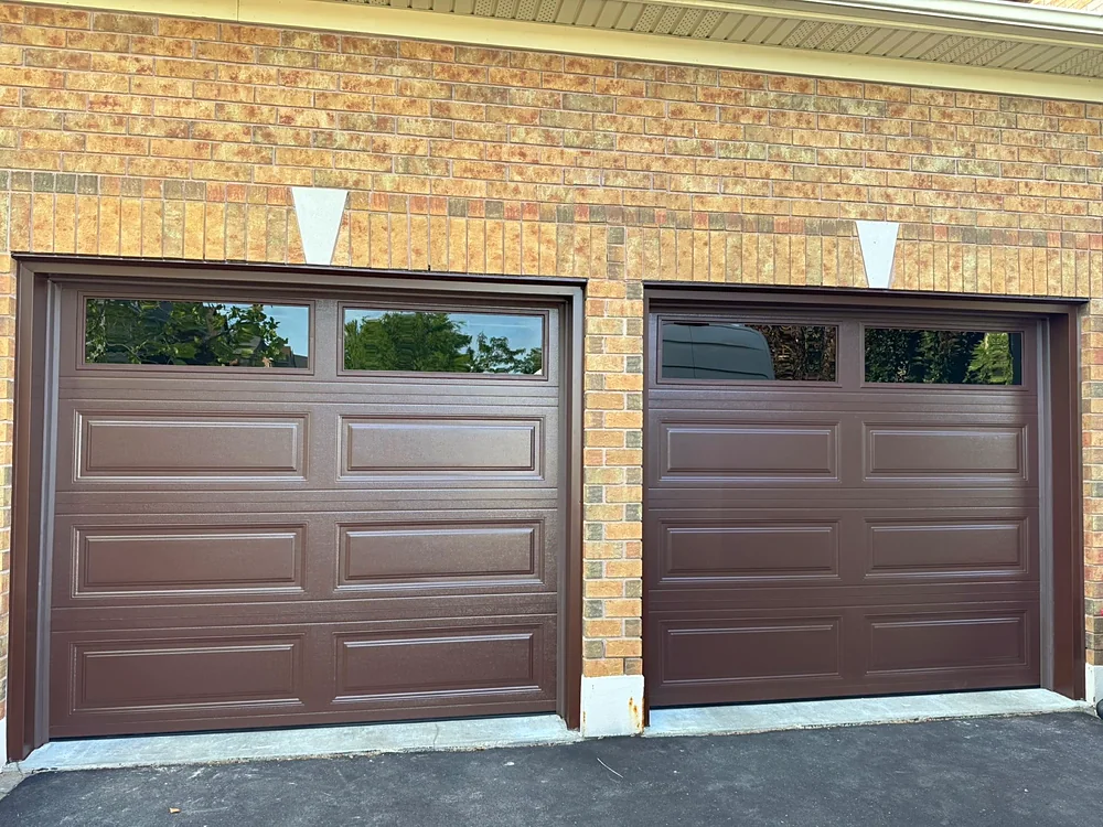 Chocolate brown long raised-panel garage doors with windows on a home in Richmond Hill