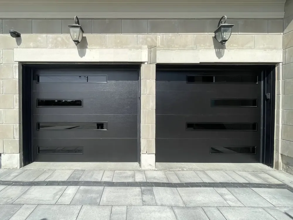 Black modern flush garage doors with slim glass strips on a home in Vaughan