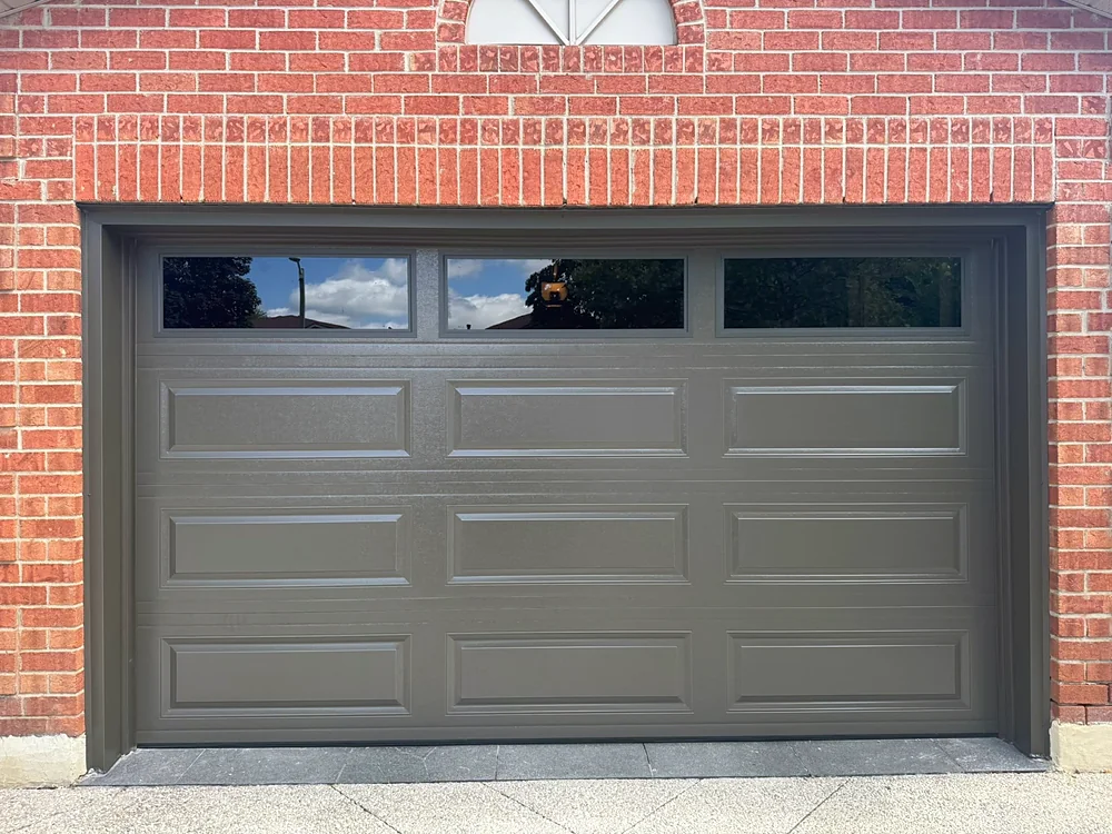Dark brown long raised-panel garage door with windows on a home in Vaughan
