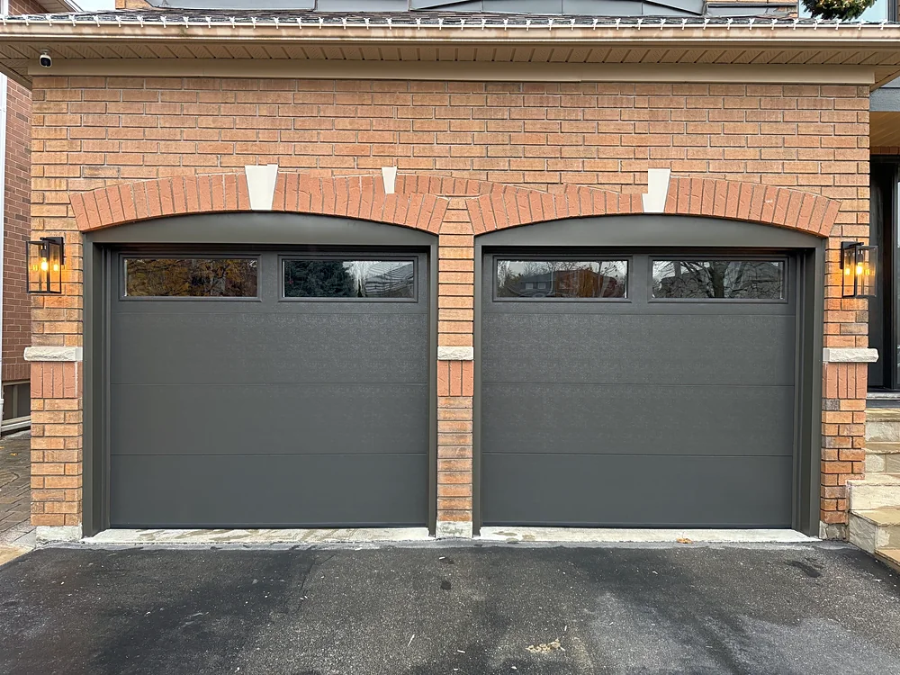 Dark brown modern flush garage doors with windows on a home in Vaughan