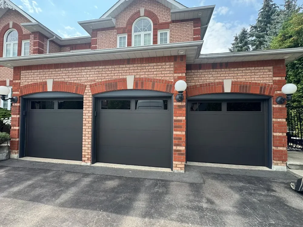 Black modern flush garage doors with windows on a home in Brampton