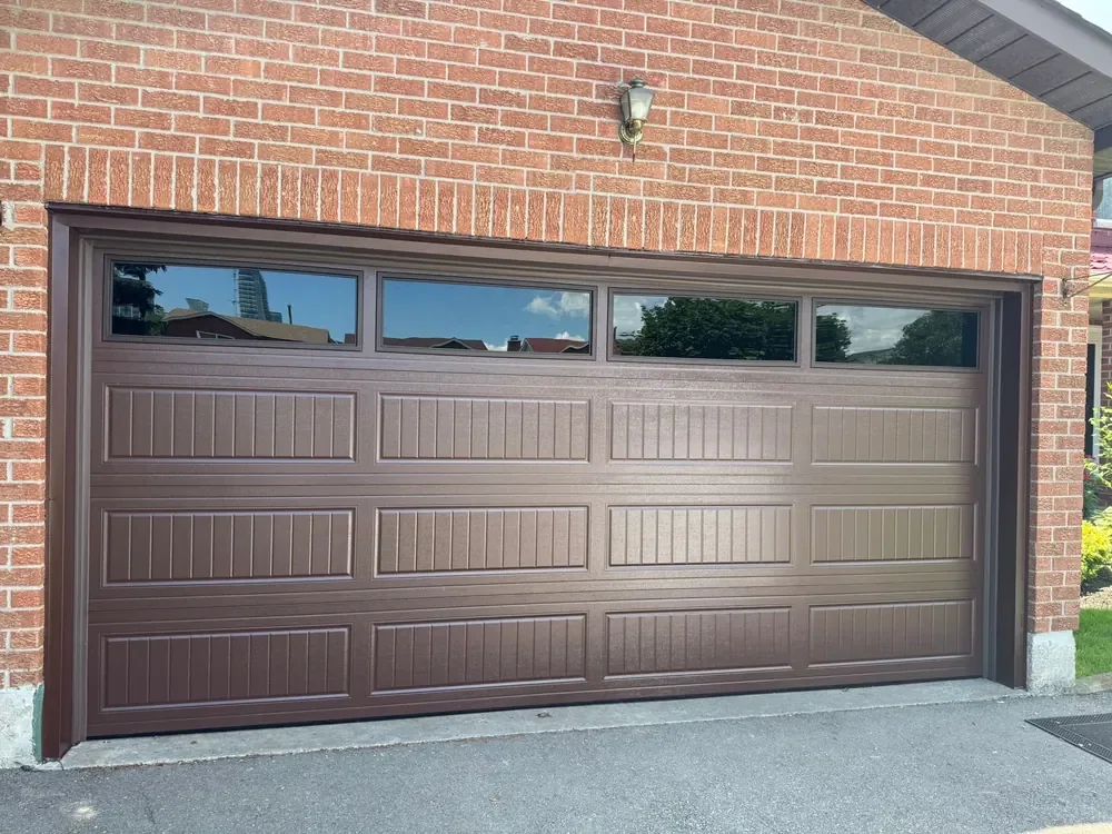 Chocolate brown carriage-house garage door with windows on a home in Burlington