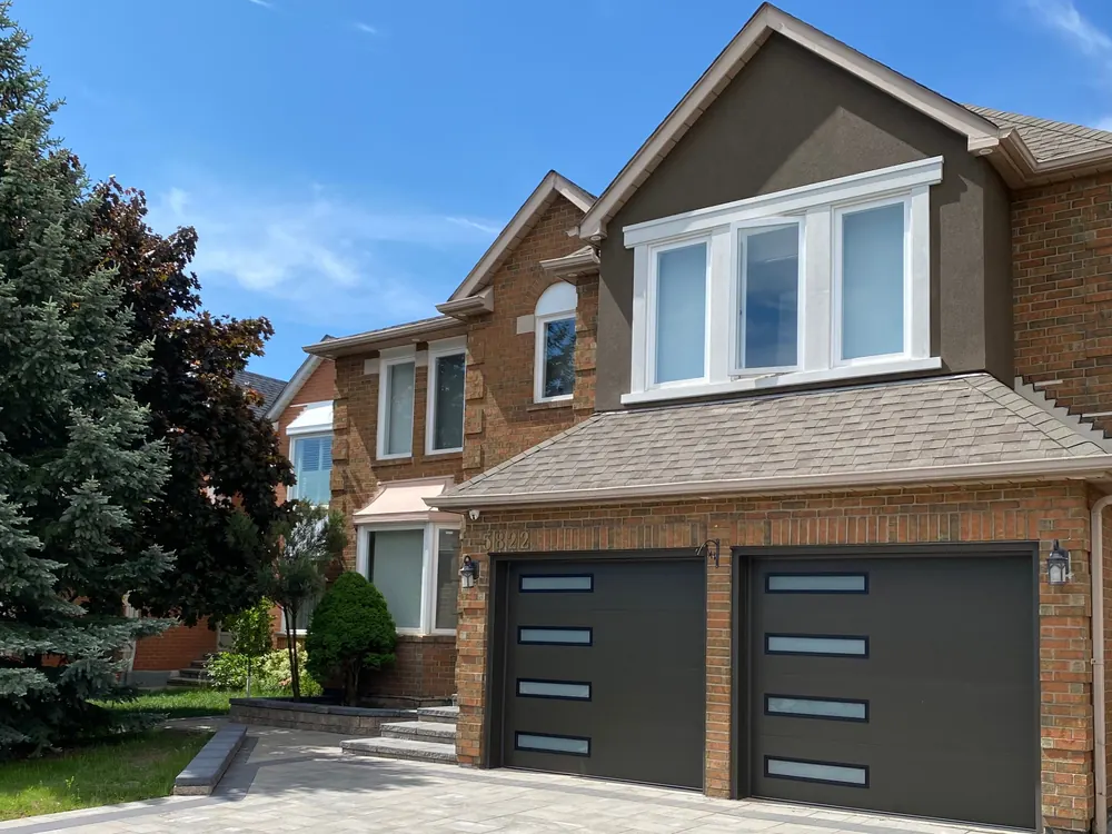 Dark brown modern flush garage doors with slim glass strips on a home in Mississauga