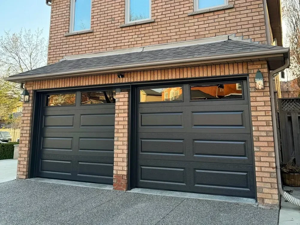 Black long raised-panel garage doors with windows on a home in Newmarket