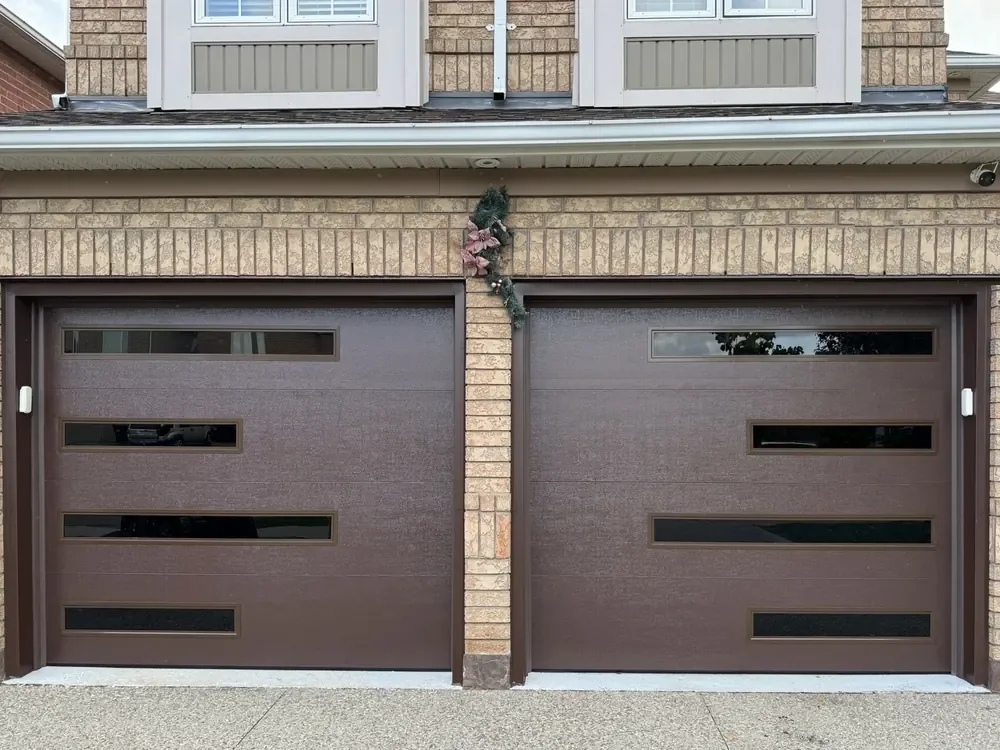 Chocolate brown modern flush garage doors with slim glass strips on a home in Pickering