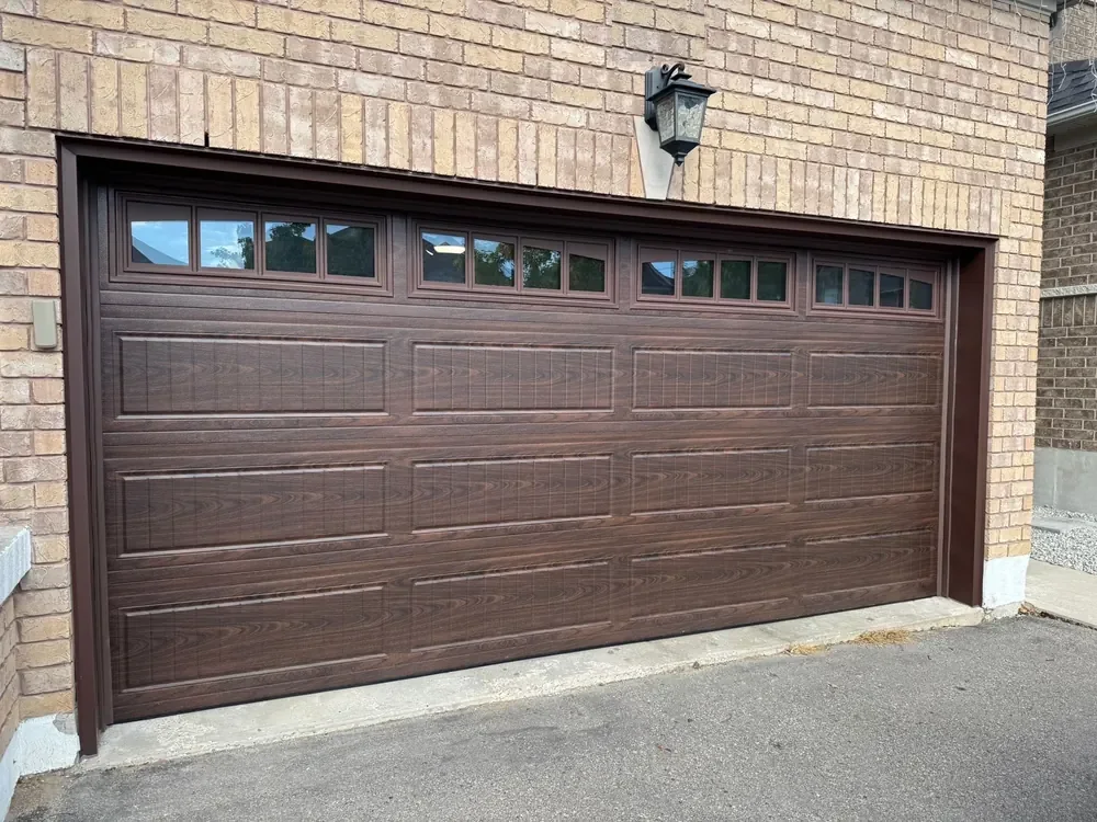 Woodgrain carriage-house garage door with windows on a home in Thornhill