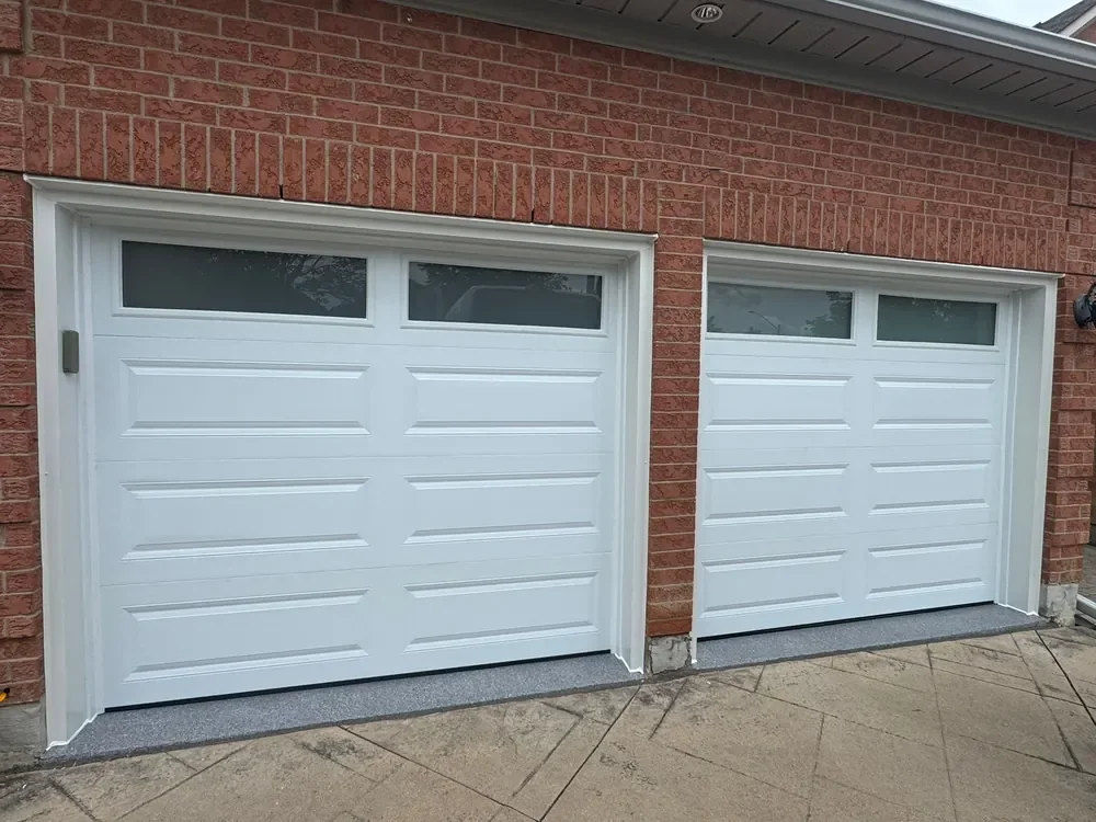 White long raised-panel garage doors with windows on a home in Whitby